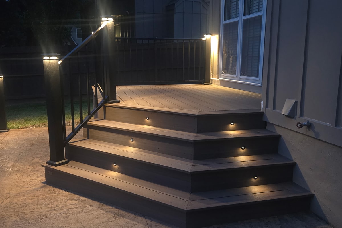 Composite deck stairs with small round recessed riser lights casting a warm glow on each step